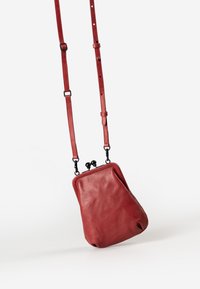 Red leather crossbody bag with a soft texture, rounded shape, clasp closure, and adjustable strap. Features black hardware accents.