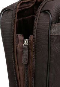 Brown, textured fabric bag interior with a silver zipper, leather accents, and a lined compartment visible inside.