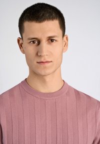 Jasnoróżowy sweter dziany, z prążkowaną teksturą i pionowymi paskami, oraz okrągłym dekoltem. Gładki materiał z subtelnymi detalami na całej powierzchni.