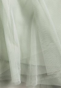 Ljusgrön tyllduk med en fin nätstruktur. Materialet är genomskinligt, med mjuka, flödande lager som ger en lätt känsla.