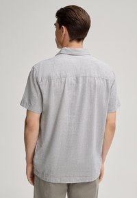 Poloshirt met korte mouwen in lichtgrijze, gestructureerde stof, voorzien van een rugpaneel en een relaxte pasvorm. Eenvoudig, schoon ontwerp zonder versieringen.