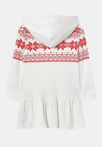 Vit huva klänning med röd nordisk mönster överst, långa ärmar, ribbstruktur och en samlad volang i fållen.