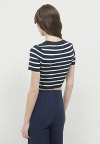 Maglia cropped a righe navy e bianche con scollatura rotonda e maniche corte, abbinata a pantaloni navy a vita alta.