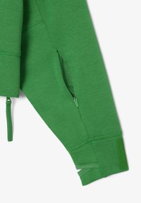 Tessuto di felpa verde con tasca laterale con zip. Presenta polsini a costine e un accento texture sull'orlo. Texture liscia; vestibilità atletica.