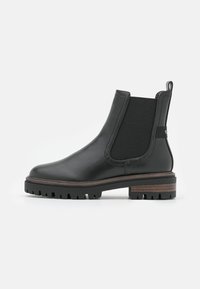 Botas Chelsea de cuero negro con paneles laterales elásticos, suela de goma texturizada y detalle de entresuela de madera. Diseño de punta redondeada.