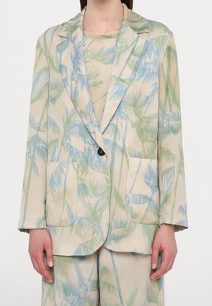 Beige blazer og matchende bukser med lys blå og grøn palmebladsprint, båret med en matchende top under.