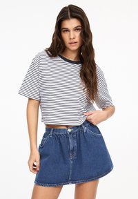 Vit kortärmad t-shirt med smala marinblå ränder och marinblå rund halsringning, kombinerad med en högmidjad denim minikjol med knapp och framfickor.