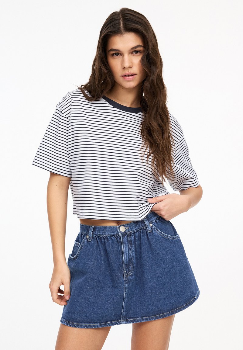 Vit kortärmad t-shirt med smala marinblå ränder och marinblå rund halsringning, kombinerad med en högmidjad denim minikjol med knapp och framfickor.