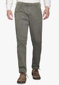 Pantaloni verde oliva da uomo in tessuto texturizzato, con chiusura a bottone, fronte piatto e gambe affusolate. Abbinate a calzature marroni.