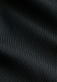 Tissu noir texturé présentant un motif de tricot ondulé, montrant des détails fins et un léger lustre sur la surface. Texture douce et lisse.