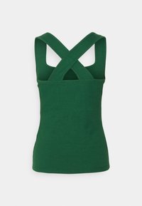 Grünes geripptes Tanktop mit taillierter Passform, überkreuzten Trägern und ohne sichtbare Hardware oder Akzente. Glatte Textur mit einem subtilen Glanz.