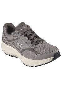 Zapatilla deportiva gris con materiales de malla y sintéticos, superposiciones texturizadas, cordones, cuello acolchado y una entresuela blanca con suela negra.