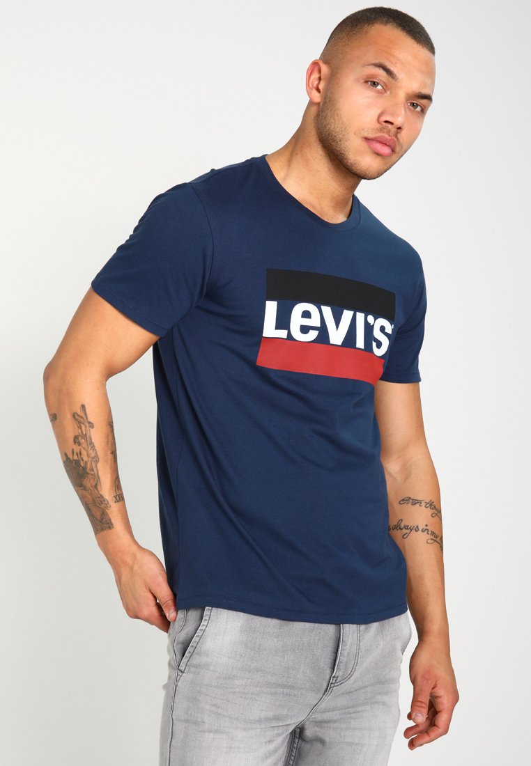Camiseta de algodón azul marino con un audaz logotipo de Levi's en blanco y rojo sobre un fondo negro. Mangas cortas, escote redondo y un corte estándar.