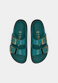Σανδάλια από καουτσούκ σε τιρκουάζ χρώμα με δύο ρυθμιζόμενες χρυσές αγκράφες, υφασμένο πέλμα και μαύρη σόλα. Μέγεθος 38, κατασκευασμένα στη Γερμανία.