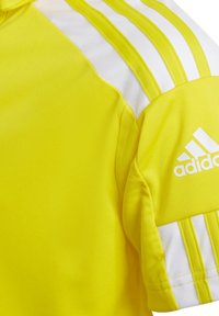 Maglietta atletica gialla in poliestere con strisce bianche sulle spalle e logo Adidas sulla manica. Texture liscia, design aderente.