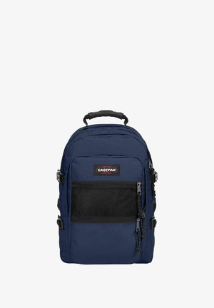 Donkerblauwe Eastpak-rugzak met zwart gaas voorvak, ritsen, zijbanden en een stevige zwarte bovengreep, getoond tegen een effen achtergrond.