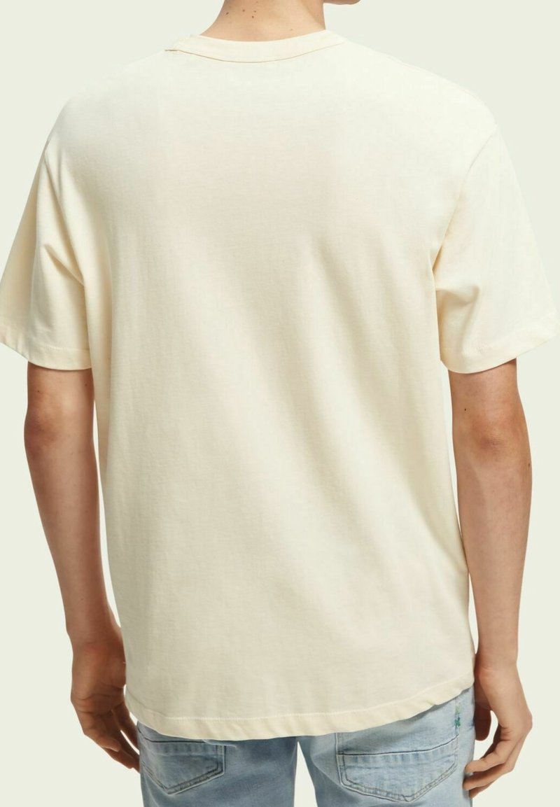 T-shirt a maniche corte di colore crema, realizzato in morbido cotone. Vestibilità ampia, scollatura rotonda e orlo pulito, con minimalistica grafica sul retro.