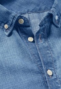 Lichtblauwe denim shirt met een button-down kraag, witte knopen, subtiele textuur en contrasterende stiksels.