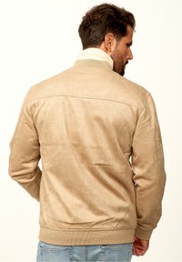 Tan suede bomber jacket with ribbed cuffs and collar, featuring a smooth texture and clean stitching on the back.