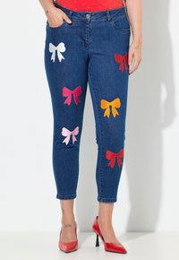 Džínové kalhoty s přiléhavým střihem, zdobené barevnými vyšívanými mašličkami v růžové, červené, bílé a oranžové barvě. Klasický design s pěti kapsami, ohrnutý lem.