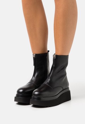 Schwarze Lederstiefeletten mit seitlichen Reißverschlüssen, runder Spitze und dicken schwarzen Plateau-Sohlen. Glatte Oberfläche und minimale Nähte.