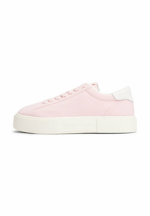 Baskets rose clair avec une tige en tissu lisse, accents de talon blancs, lacets plats et une semelle blanche épaisse et texturée. Logo "TOMMY JEANS" sur le côté.