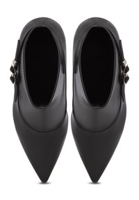 Černé kožené kotníkové boty s špičatou špičkou, s hladkým povrchem a dekorativními přezkami po straně.