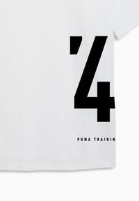 T-shirt en coton blanc avec un grand motif noir comprenant le chiffre « 24 » et le texte « PUMA TRAINING » en police épaisse sur le côté inférieur.