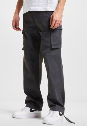 Donkergrijze cargobroek van katoen met zijzakken en een ontspannen pasvorm, gecombineerd met witte sneakers met zwarte accenten.