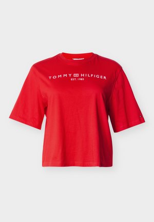 Punane lühikeste varrukatega t-särk, valmistatud puuvillast, millel on ümara kaelusega ja ees rinnal valge "TOMMY HILFIGER EST. 1985" logo.