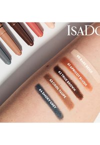 Cinq teintes de crayons à maquillage disposées au-dessus d'un bras sur lequel sont appliquées cinq couleurs correspondantes : beige, abricot, marron, taupe, gris.