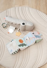 Zachte babyknuffel krokodil met aangehechte bijtring, spiegel en stoffen boek met dierenillustraties op een beige gewatteerde speelmat.