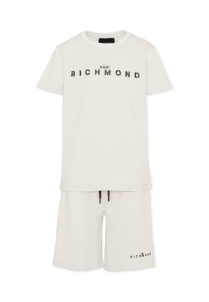 Biały zestaw t-shirt i szorty z napisem „John Richmond” nadrukowanym na klatce piersiowej i lewej nodze szortów.