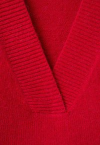 Pull en tricot rouge avec un décolleté en V plongeant, des accents côtelés sur les bords et une finition texturée douce.