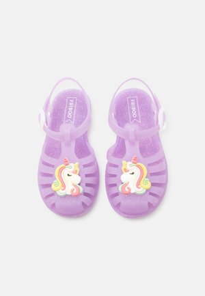 Fioletowe brokatowe sandałki dla malucha z paskami wokół kostki, każdy z kolorową dekoracją jednorożca z przodu.