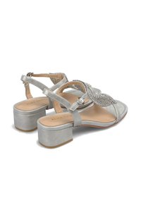 Zilverkleurige sandalen met blokhak en een tekstuurriem versierd met rhinestones. Voorzien van een verstelbare enkelband en een open teen ontwerp.