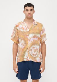 Camisa de manga corta abotonada con un patrón de tie-dye en tonos de naranja, amarillo y blanco. Tejido ligero, corte relajado y cuello con muesca.