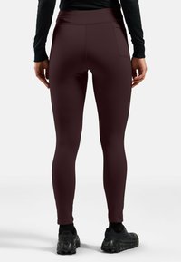 Bordeauxkleurige leggings met een hoge tailleband, een gladde textuur en een zijzak. Draag met zwarte sportschoenen. Achteraanzicht getoond.