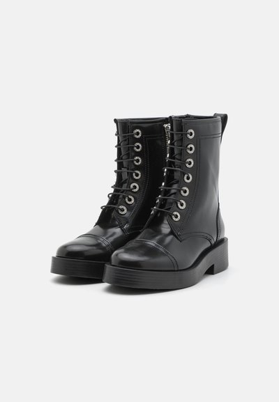 Botas de cuero negras hasta el tobillo con un acabado texturizado, diseño con cordones, puntera redonda, costuras prominentes y herrajes de ojales plateados.