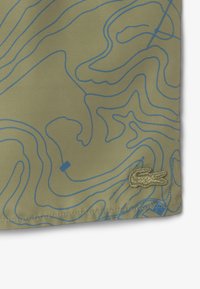 Khaki stof met een patroon van blauwe contourlijnen; heeft een geborduurd logo aan de zoom. Soepele textuur met een lichtgewicht ontwerp.