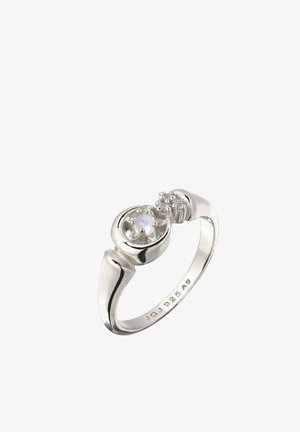 Zilveren ring met een centrale witte parel en een kleine verhoogde cluster van zilveren kralen aan één kant, gemarkeerd met 925 Ag aan de binnenkant van de band.