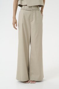 Lys beige vide benbukser med et pinstripe-mønster, belted midje og sidelommer; parret med hvite stroppesandaler.