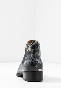 Botas de tobillo de piel de serpiente negras y azules con paneles laterales elásticos, un tacón bajo y un patrón de superficie texturizado.