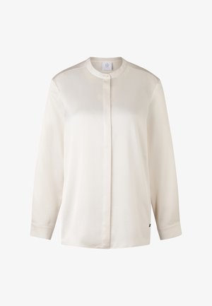 Cream-colored long-sleeve shirt with a mandarin collar, button closure, smooth texture, and a subtle sheen. Features a side label accent.