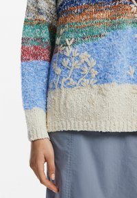 Többszínű kötött pulóver, texturált anyagból. Kék, zöld és krémszínű részekkel rendelkezik, virágmintás hímzéssel és bordás mandzsettákkal.