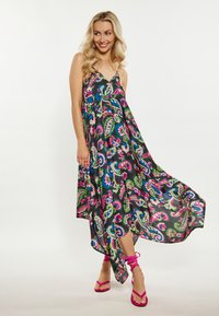 Rochie maxi dintr-un material ușor, cu un model paisley colorat. Are bretele subțiri și o margine asimetrică. Este asociată cu sandale roz cu curea.