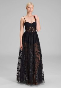 Schwarzes Abendkleid mit einem eng anliegenden Spitzen-Oberteil, transparenter Tüll-Rock und floralen Stickereien. Enthält Spaghettiträger und eine fließende Silhouette.