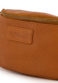 Brązowa skórzana torba z złotym zamkiem błyskawicznym, wytłoczone logo "VENEZIA", gładka tekstura, zaokrąglony kształt, zaprojektowana do przechowywania akcesoriów lub kosmetyków.