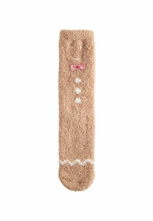 Soft, beige sock with fluffy texture. Features a smiling face, red checkered bow tie, white buttons, and zigzag pattern at the bottom.