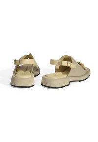 Beige Wildledersandalen mit geschlossener Zehenpartie, verstellbarem Knöchelriemen, strukturiertem Innensohle und schwarzem Gummisohle. Mit einer Schnallen-Detailakzentuiert.